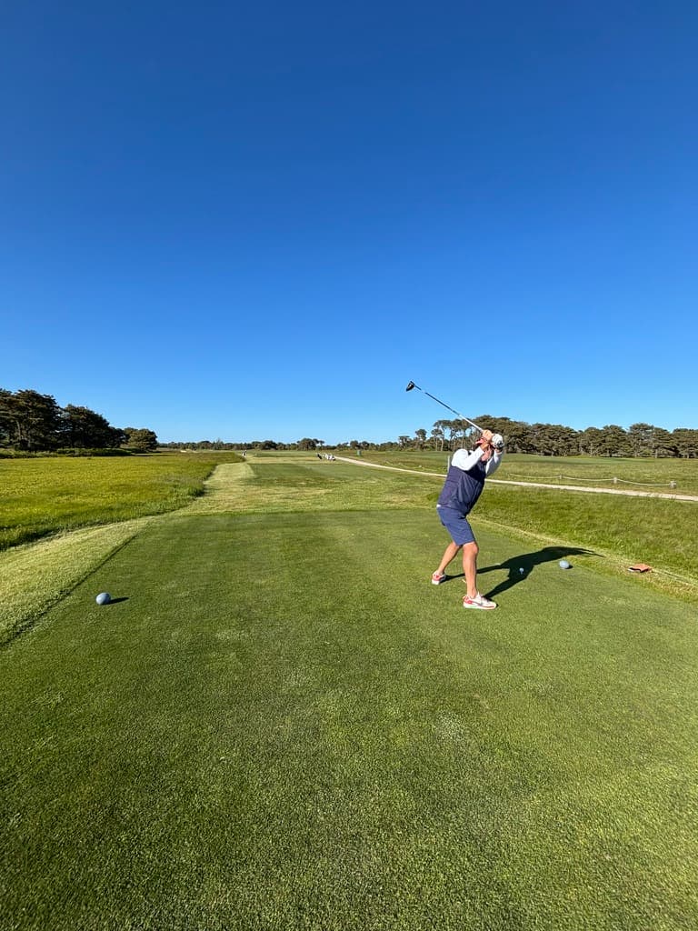A golfer mid-swing on a Dallas-area course on a clear day.